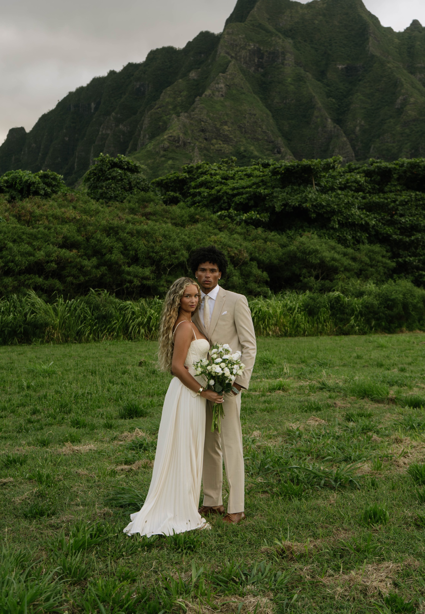 Eloping couple embracing in front of the Koʻolau mountains